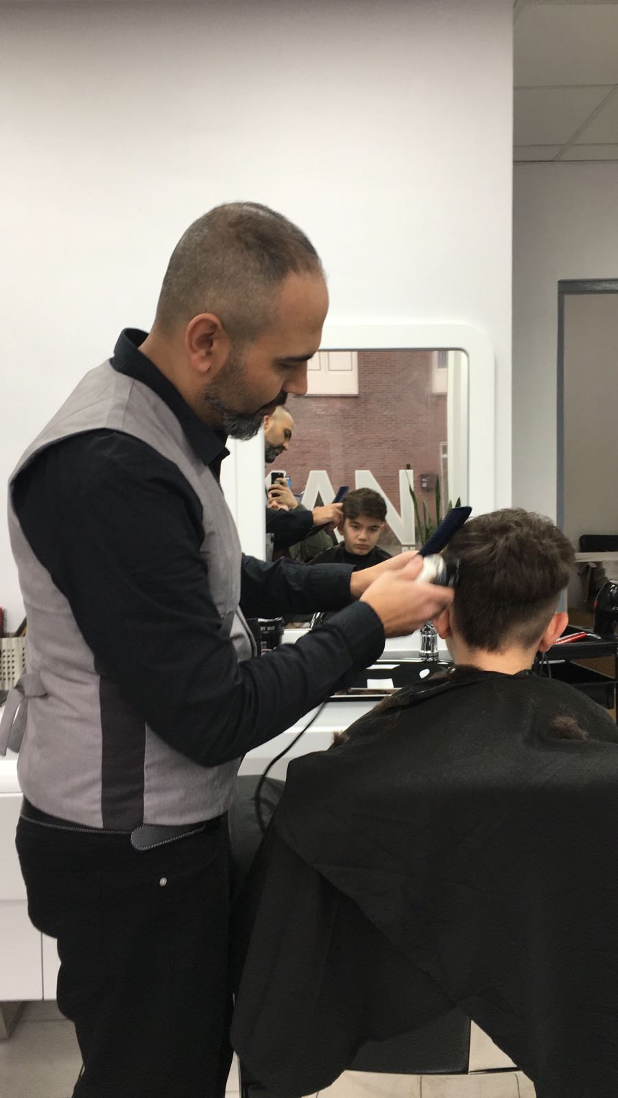 De kapper knipt een jongen met de tondeuse